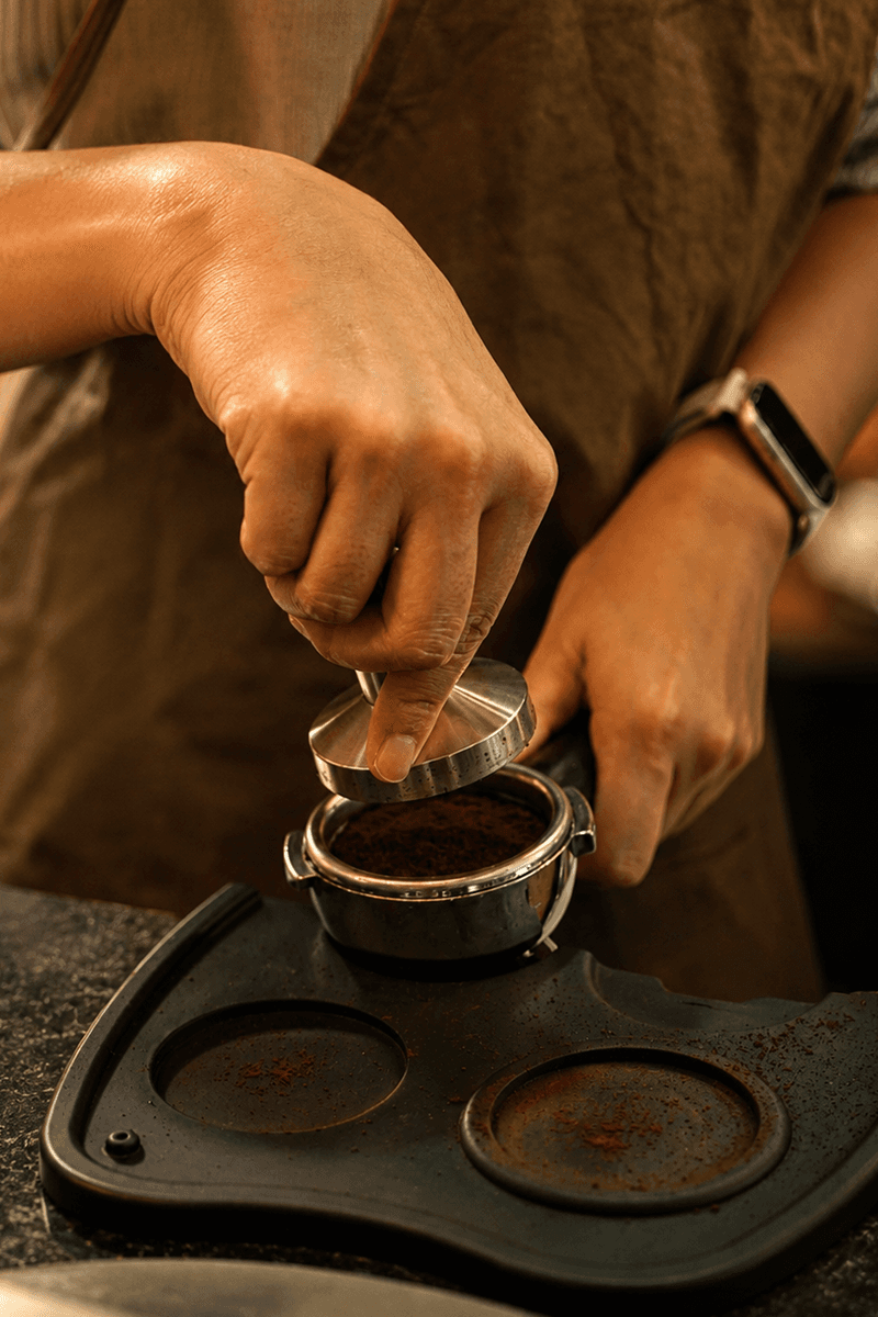 Barista tamping fresh ground coffee at Beezy